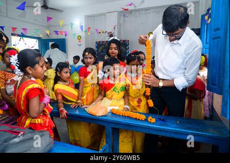 La Nabin Nagar Primary School è una remota scuola rurale situata a Nabin Nagar, lungo il confine tra India e Bangladesh. Nonostante le sfide, la scuola celebra il giorno degli insegnanti il 5 settembre, in occasione del compleanno del Dr. Sarvepalli Radhakrishnan, secondo presidente dell'India. Il preside della scuola prende l'iniziativa di organizzare la celebrazione, preparando ghirlande di fiori di calendula per le sue studentesse prima della loro esibizione di danza. Nabin Nagar, Bengala Occidentale, India. Foto Stock