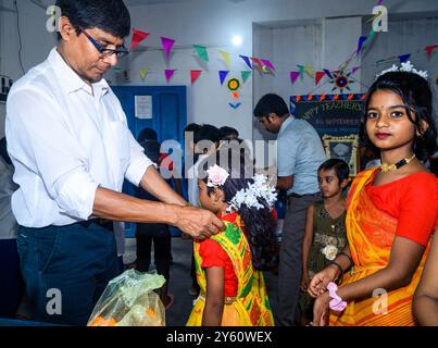 La Nabin Nagar Primary School è una remota scuola rurale situata a Nabin Nagar, lungo il confine tra India e Bangladesh. Nonostante le sfide, la scuola celebra il giorno degli insegnanti il 5 settembre, in occasione del compleanno del Dr. Sarvepalli Radhakrishnan, secondo presidente dell'India. Il preside della scuola prende l'iniziativa di organizzare la celebrazione, preparando ghirlande di fiori di calendula per le sue studentesse prima della loro esibizione di danza. Nabin Nagar, Bengala Occidentale, India. Foto Stock