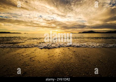 Una lunga pausa al tramonto su una spiaggia mediterranea, il movimento dell'acqua, l'ora d'oro e il paesaggio ispirano tranquillità e pienezza Foto Stock