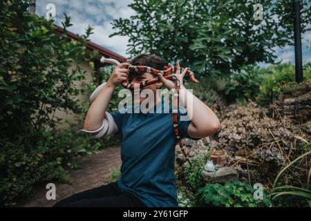 Ragazza che gioca con gioia con i serpenti in un giardino lussureggiante Foto Stock