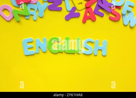 Parola inglese colorata su sfondo giallo composta da lettere alfabetiche abc colorate con spazio di copia per testo o design. Imparare o educare gli inglesi Foto Stock