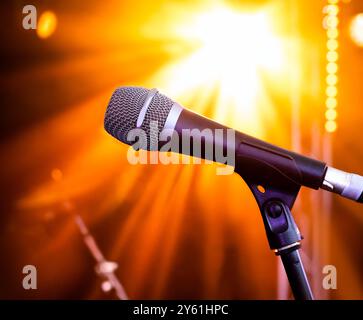 Microfono sul palco con luci luminose. Illuminazione ambientale del palco con microfono vocale e strumenti musicali dal vivo sfocati sullo sfondo. Foto Stock