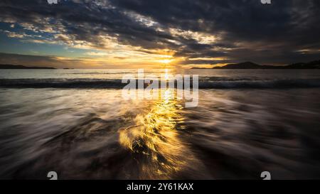 Una lunga pausa al tramonto su una spiaggia mediterranea, il movimento dell'acqua, l'ora d'oro e il paesaggio ispirano tranquillità e pienezza Foto Stock