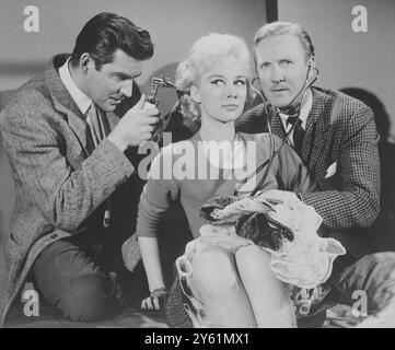 MICHAEL CRAIG E LESLIE PHILLIPS ESAMINANO CAROLE LESLEY DURANTE LE RIPRESE DI DOCTORS IN LOVE 17 MARZO 1960 Foto Stock