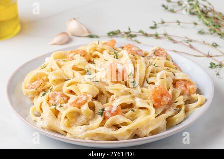 Cremosi gamberi fettuccine Alfredo guarnite con timo fresco, parmigiano, aglio, olio d'oliva e una spolverata di grani di pepe. Cucina italiana Foto Stock