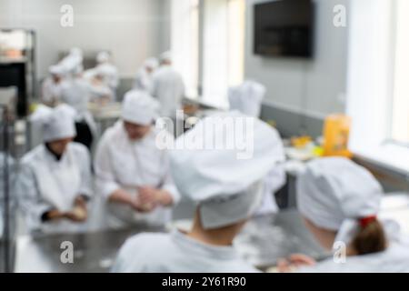 Team di panettieri che lavorano in cucina, immagine offuscata della produzione culinaria o panetteria. Foto di alta qualità Foto Stock