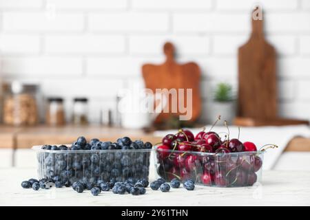 Contenitori in plastica con frutti di bosco freschi sul tavolo in cucina Foto Stock