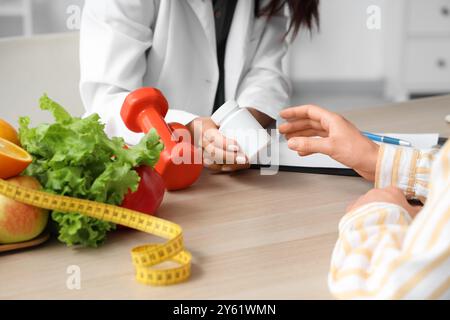 Nutrizionista femminile che consegna il flacone di pillola al paziente in ufficio, primo piano Foto Stock