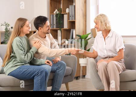 Psicologa donna che stringe la mano a una giovane coppia in ufficio Foto Stock