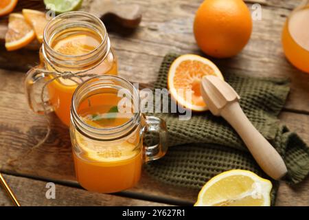 Vasetti Mason di succo d'arancia fresco con agrumi e centrifuga su fondo in legno Foto Stock