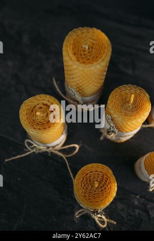 Cinque candele a nido d'ape fatte a mano si trovano su uno sfondo scuro, illuminato dalla luce naturale. Foto Stock