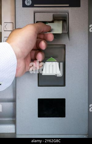 Primo piano dell'uomo l'inserimento di carta di credito nella macchina ATM Foto Stock