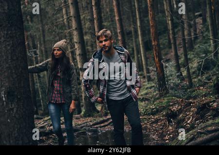 Percorso difficile. Bella giovane coppia che cammina insieme nel bosco mentre si gode il loro viaggio Foto Stock