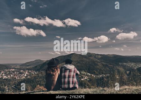 Le migliori vacanze. Vista posteriore di giovani coppie che ammirano la vista mentre si siede sulla cima della montagna Foto Stock