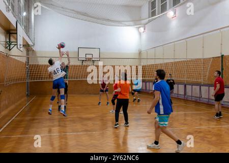 Giocatori dilettanti di pallavolo che saltano in piedi in posizione difensiva sul campo coperto. Pallavolo con squadre di uomini, donne e co-ed. B Foto Stock