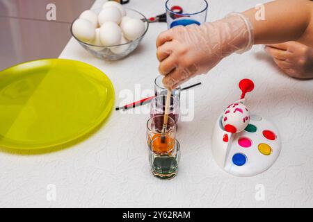 Primo piano di bambini che dipingono uova di Pasqua con colori brillanti durante l'attività creativa a casa. Svezia. Foto Stock