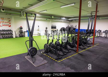 Palestra CrossFit con attrezzature per esercizi, tra cui cyclette e area sollevamento pesi, pronta per l'allenamento. Foto Stock