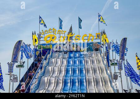 Monaco, Baviera, Germania - 23 settembre 2024: Lo scivolo di Monaco all'Oktoberfest offre divertimento per grandi e piccini. Lo scivolo blu e bianco è una delle giostre più popolari di Wiesn lo scivolo blu e bianco è una delle giostre più popolari di Wiesn *** Die Münchner Rutsche auf dem Oktoberfest bietet Spaß für Groß und Klein. Die blau-weiße Rutsche ist eines der beliebten Fahrgeschäfte der Wiesn Foto Stock