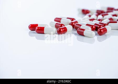 Capsule rosse bianche sparse su sfondo bianco illustrano il percorso di scoperta di farmaci dal laboratorio al mercato. Processo di innovazione farmaceutica Foto Stock