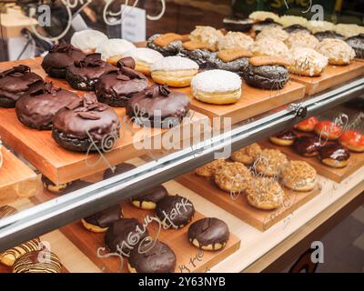 Ciambelle di vari sapori e condimenti esposte in una bancarella di cibo locale Foto Stock