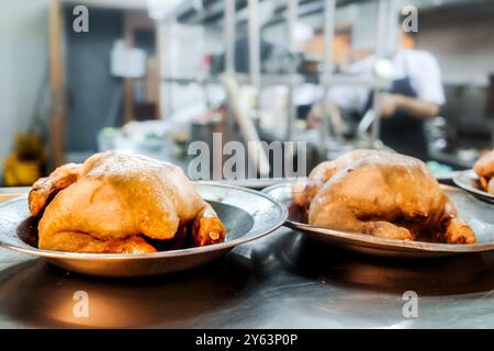 Menu di carne di pollo preparato nella cucina di un ristorante con chef e personale che lavorano sullo sfondo Foto Stock
