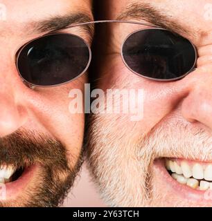 Occhiali da uomo. Due Beardeds di mezza età indossano occhiali guardando la fotocamera con una espressione seria. Concetto di occhiali. Uomo anziano con figlio. Foto Stock