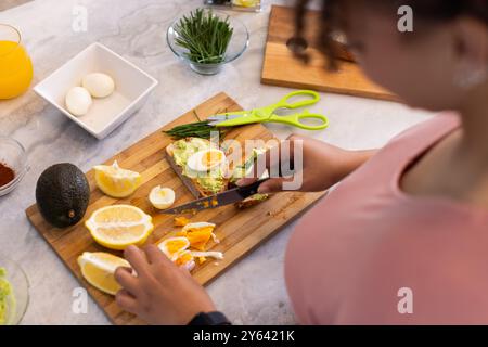 Preparare un pasto sano, donna affettare il limone e uova bollite sul tagliere, a casa, a casa Foto Stock