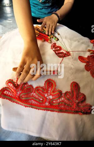 Una donna che unisce motivi decorativi su tessuti utilizzando lo strumento tradizionale a Sawahlunto, West Sumatra, Indonesia. Foto Stock