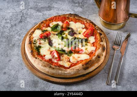 Pizza Margherita napoletana con pomodori, mozzarella, basilico e olive su tavola di pietra Foto Stock
