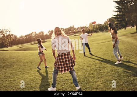 Divertirsi con gli amici. Tutti i giovani in abbigliamento casual giocano a frisbee mentre trascorrono del tempo libero all'aperto Foto Stock