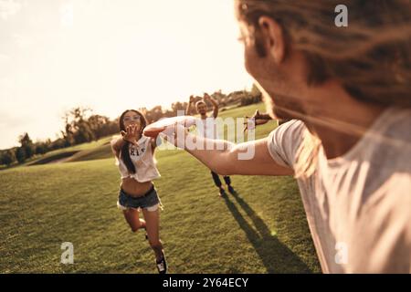 Prendilo! Gruppo di giovani in abbigliamento casual che giocano a frisbee mentre trascorrono del tempo libero all'aperto Foto Stock