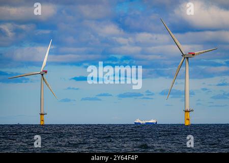 Foto del file datata 26/07/22, di una nave che passa per turbine eoliche a Gwynt y Mor della RWE, il secondo parco eolico offshore più grande del mondo, situato al largo della costa del Galles del Nord. La Commissione per una transizione giusta della Scozia illustrerà oggi le lezioni chiave derivanti dall'esperienza delle Shetland in materia di transizione energetica, che ritiene possa contribuire a definire risultati più equi per le comunità di tutto il paese. Data di pubblicazione: Martedì 24 settembre 2024. Foto Stock