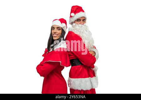 Una coppia gioiosa vestita con abiti di Babbo Natale si staglia dietro le quinte e guarda la telecamera con un sorriso. Il loro atteggiamento allegro cattura le feste Foto Stock