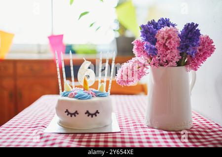 Bellissima torta di compleanno in forma di unicorno con sei candele e un mucchio di giacinti. Concetto del sesto compleanno. Ragazzo che festeggia il sesto compleanno Foto Stock