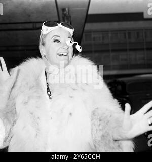 Phyllis Diller , la più grande comica di stand-up del mondo , arriva all' aeroporto di Londra e si mette subito in scena nel suo gesto divertente, mentre bilancia precariamente un bizzarro oculare di plastica . È qui per registrare un Liberace Show per ATV , e spera di inserirsi in un Eamonn Andrews Show nel suo fitto programma . La signorina Diller, 51 anni, ha 5 figli e 2 figliastri, e dice: »Sono tutti in vendita». Vive con il marito attore Warde Donovan in una casa di 22 stanze a Los Angeles , possiede 8 auto e 12 pianoforti . 14 febbraio 1969 Foto Stock