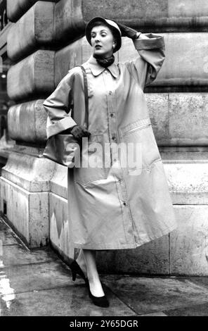 La pioggia è caduta e ha obbligato la modella Joanna Riley quando ha esposto questo impermeabile gabardine di cotone a prova di cotone ad una rappresentazione di cappotti da donna Aquascutum Autunno e Inverno 1953 e abbigliamento da pioggia alla moda , tenutasi nella zona ovest di Londra . Intitolato Mariner , e venduto al dettaglio a circa 12 ghinee , il cappotto presenta linee sciolte , enormi tasche con zip e cappello con cuciture coordinate . 30 aprile 1953 Foto Stock