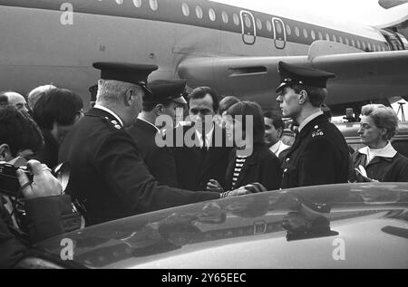 La polizia dell' aeroporto di Londra accompagna Davy Jones , cantante del gruppo pop americano The Monkees in una macchina in attesa , poco dopo il suo arrivo dall' America . La scorta era per la sua stessa protezione. Quasi 800 fan si sono scontrati con la polizia e hanno urlato attraverso l' edificio del terminal , causando il caos tra i passeggeri in attesa . 13 febbraio 1967 Foto Stock