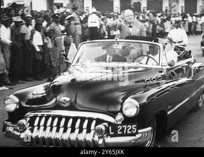 Il benvenuto del signor Churchill in Giamaica. Seduto sul retro di un' auto americana liscia e lucida , il primo ministro Winston Churchill dà il suo cartello con la V in tempo di guerra alla folla di Montego Bay , Giamaica , mentre viene guidato per le strade poco dopo il suo arrivo qui dagli Stati Uniti . Seduto con lui alle spalle c'è Sir Hugh Foot , il governatore di questa soleggiata isola delle Indie occidentali britanniche . 13 gennaio 1953 Foto Stock