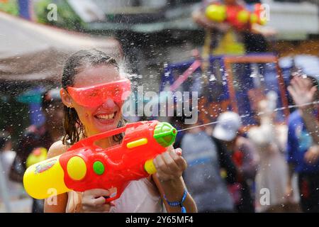 Bangkok, Thailandia - 13 aprile 2023: Donna spruzza acqua con una pistola ad acqua durante il tradizionale festival di Songkran, Capodanno tailandese, in Khaosan Road. Foto Stock