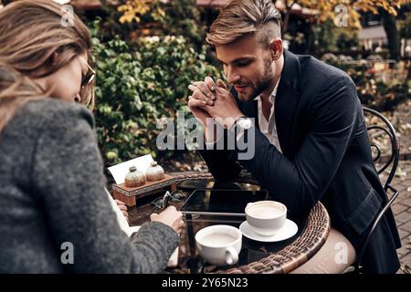 Bel discorso d'affari. Bel giovane uomo in abbigliamento casual elegante sorridente mentre parla con una giovane donna al ristorante Foto Stock