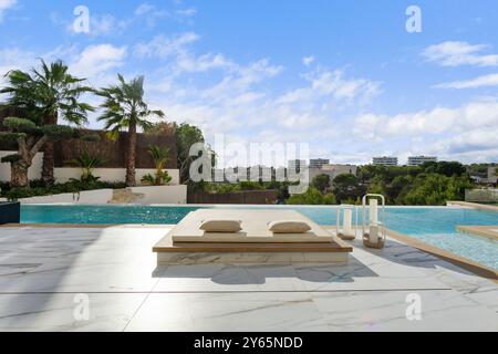 Questa villa di lusso dispone di una splendida piscina a sfioro circondata da lussureggianti palme, offrendo una fuga esclusiva e serena Foto Stock