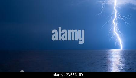 Un potente fulmine colpisce il Mar Nero al largo della costa della regione dell'Adjara in Georgia, illuminando il cielo notturno tempestoso con un intenso ed elettrico Foto Stock