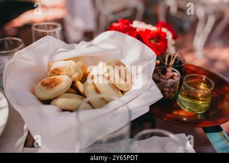 Una disposizione di tè alla menta marocchino e pane fresco, servito all'aperto con rose rosse, cattura l'essenza di un piacevole pomeriggio a Marrakec Foto Stock