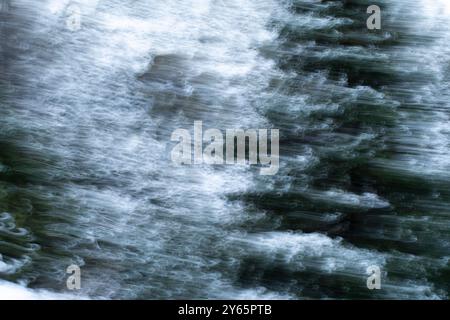 Questa immagine astratta presenta una trama nevosa e fluida catturata in scala di grigi e verde, che evoca un senso di movimento e fluidità Foto Stock