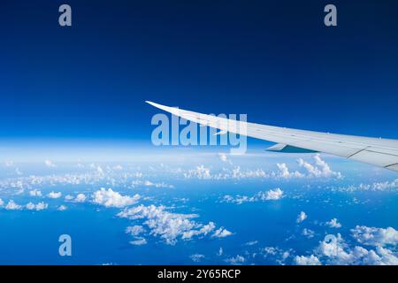 Tranquilla scena di un'ala di un aereo che si innalza sopra soffici nuvole bianche contro un cielo blu limpido. Foto Stock