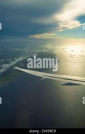Accattivante foto aeree che catturano la costa e le formazioni di nuvole viste dal punto panoramico di un'ala di un aereo durante un volo tranquillo. Foto Stock