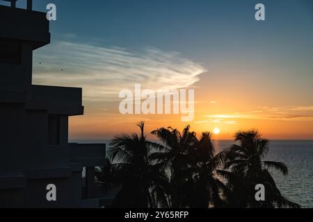 Un tranquillo tramonto catturato da un edificio contemporaneo, caratterizzato da palme sagomate contro un cielo vibrante sopra Varadero Beach, Cuba Foto Stock