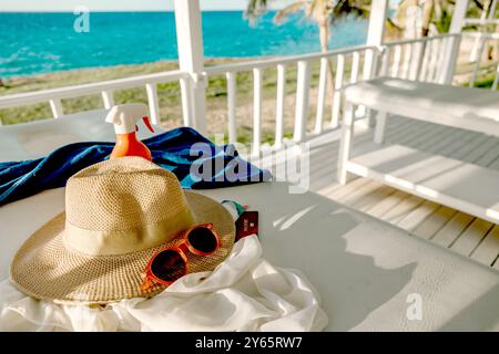 Un'invitante scena tropicale mette in mostra accessori per le vacanze su un luminoso balcone che si affaccia sulla tranquilla spiaggia e sul mare blu di Varadero, Cuba. Foto Stock
