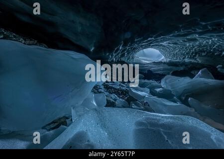 Un'affascinante scena invernale all'interno di una grotta di ghiaccio, che illustra un arco naturale fatto di ghiaccio traslucido, delicatamente illuminato da un'apertura alla fine, Foto Stock