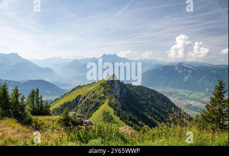 Splendida vista panoramica da un sentiero escursionistico nelle Alpi Svizzere che presenta una vegetazione vivace, montagne torreggianti e valli lontane sotto un blu chiaro Foto Stock